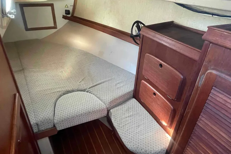 Slide: The Image of 1989 Island Packet 35 sailboat interior cabin with bed and wooden storage drawers. - 34