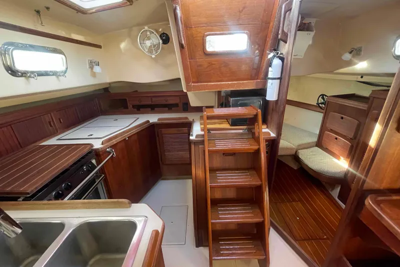 Slide: The Image of 1989 Island Packet 35 yacht interior with wooden cabinetry, kitchen, and seating area. - 4