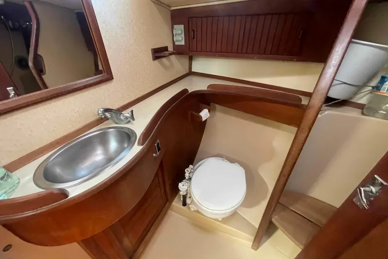Slide: The Image of 1989 Island Packet 35 yacht bathroom with sink, toilet, and wooden cabinetry. - 43