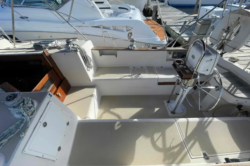 Slide: The Image of 1989 Island Packet 35 sailboat cockpit with steering wheel and seating, docked at marina. - 59