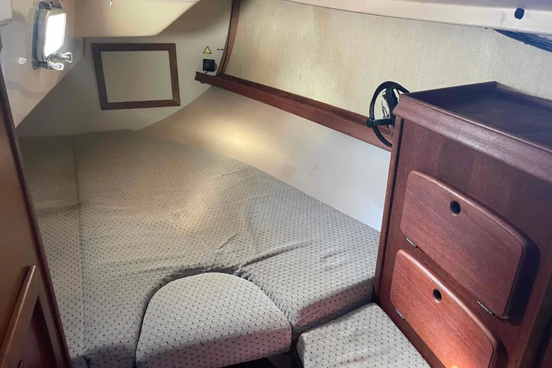 Slide: The Image of 1989 Island Packet 35 sailboat interior cabin with cozy bed and wooden storage. - 7