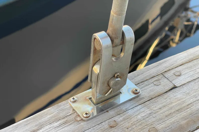 Slide: The Image of 1989 Island Packet 35 sailboat deck with winch and railing, docked in calm waters. - 78