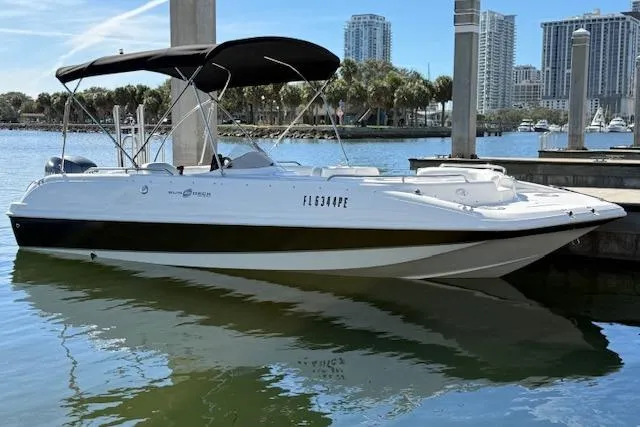 Slide: The Image of 2011 Hurricane SunDeck Sport 201 OB boat docked in a marina with city skyline. - 10