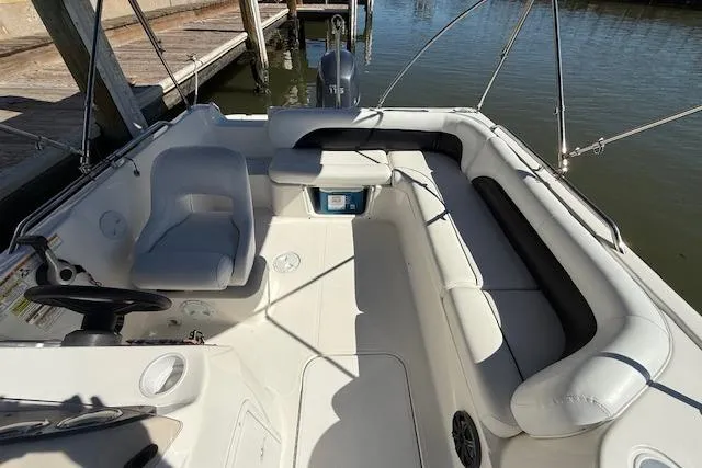Slide: The Image of 2011 Hurricane SunDeck Sport 201 OB boat interior with seating and steering wheel, docked by water. - 16