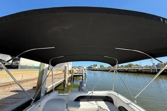 Slide: The Image of 2011 Hurricane SunDeck Sport 201 OB boat with canopy, docked at a marina. - 22