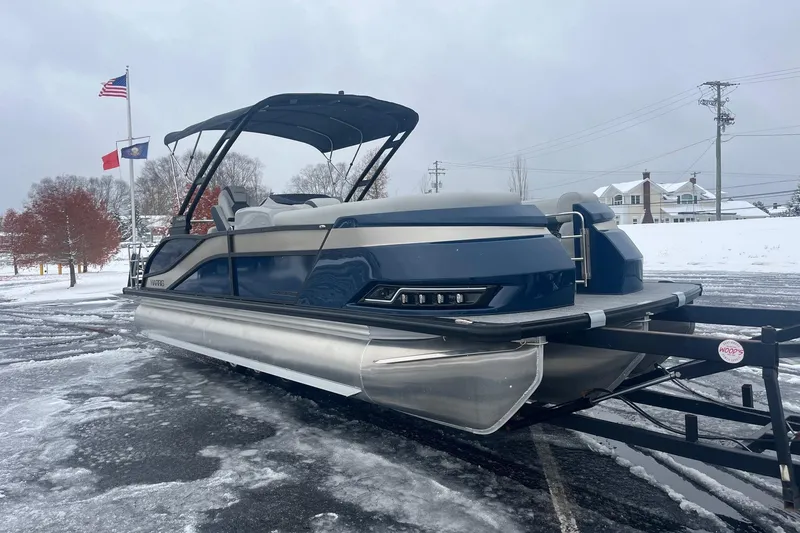 Slide: The Image of 2026 Harris Grand Mariner 230 pontoon boat on snowy ground, flags in background. - 7
