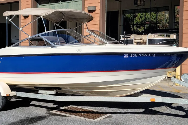 The Image of 2004 Bayliner 215 Classic boat on trailer, blue and white exterior, parked outdoors. - 0