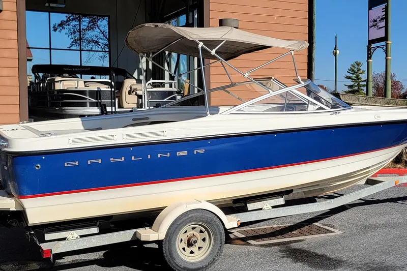 Slide: The Image of 2004 Bayliner 215 Classic boat on trailer, blue and white exterior, parked outdoors. - 1