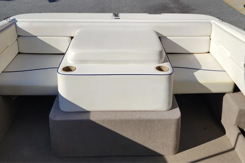 Slide: The Image of 2004 Bayliner 215 Classic boat interior with white cushioned seating and cup holders. - 7