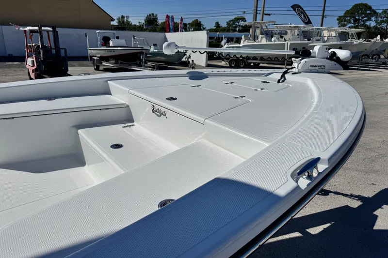 Slide: The Image of 2026 BlackJack 224 boat, sleek white deck, parked outdoors in a marina. - 7