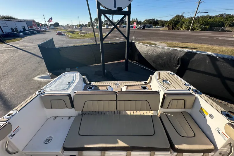 Slide: The Image of 2022 Yamaha Boats 252 FSH Sport interior with seating and cup holders, parked outdoors. - 100