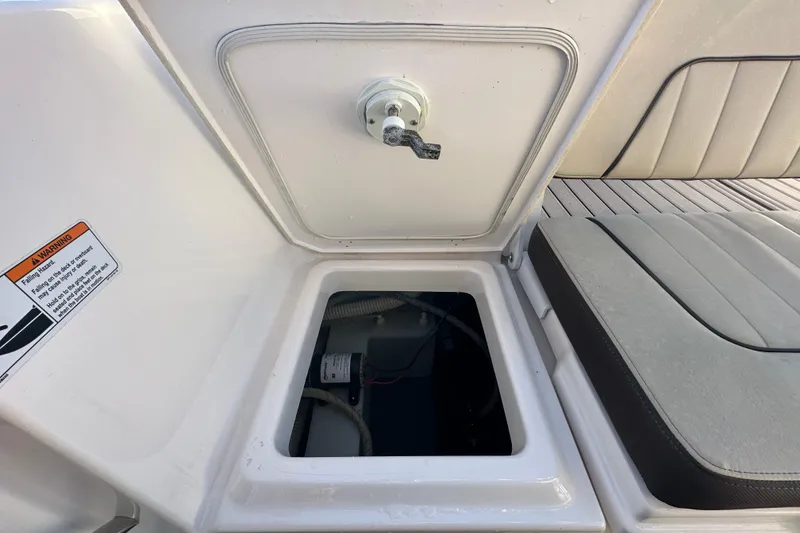 Slide: The Image of 2022 Yamaha Boats 252 FSH Sport storage compartment with open hatch and warning label. - 103