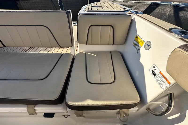 Slide: The Image of 2022 Yamaha Boats 252 FSH Sport interior seating with beige cushions and safety labels. - 109