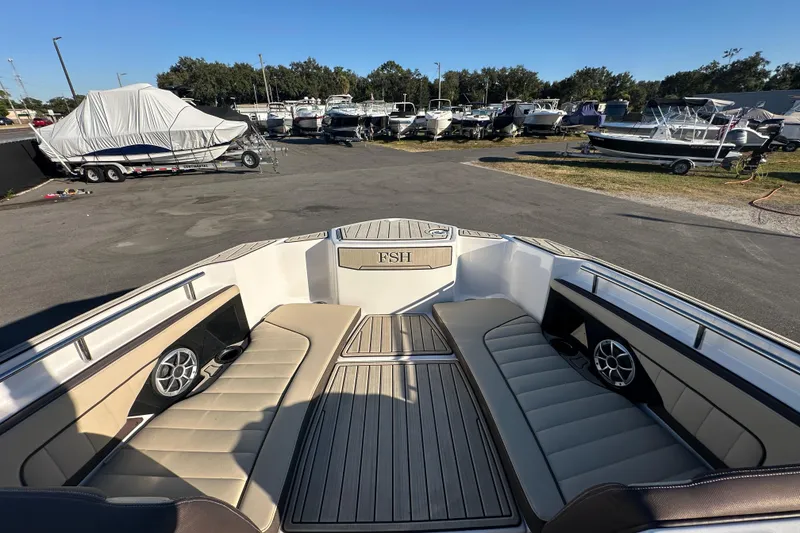 Slide: The Image of 2022 Yamaha Boats 252 FSH Sport interior with seating and speakers at a marina. - 61
