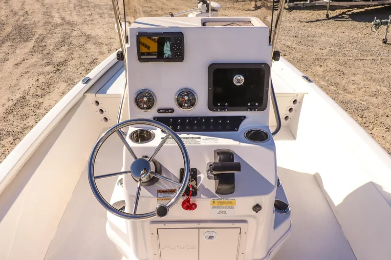 Slide: The Image of 2023 Avid 19 FS boat console with steering wheel, gauges, and navigation system. - 12