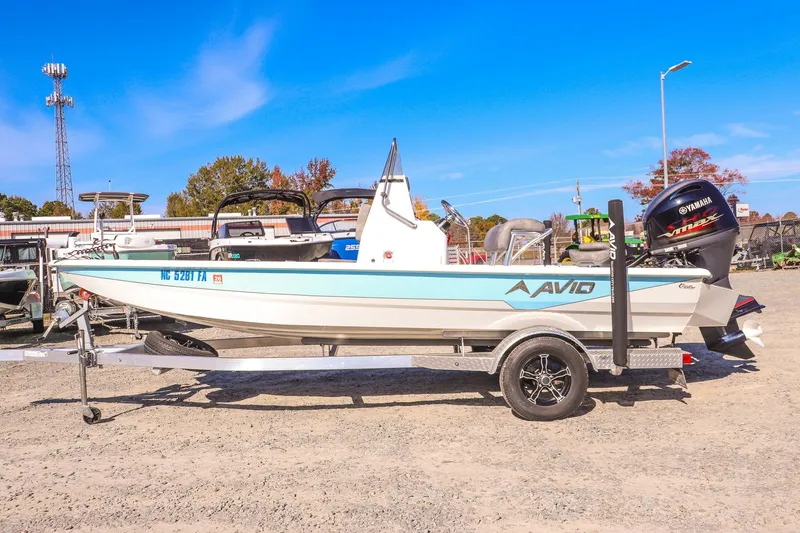 Slide: The Image of 2023 Avid 19 FS boat on trailer, featuring Yamaha engine, parked outdoors. - 7