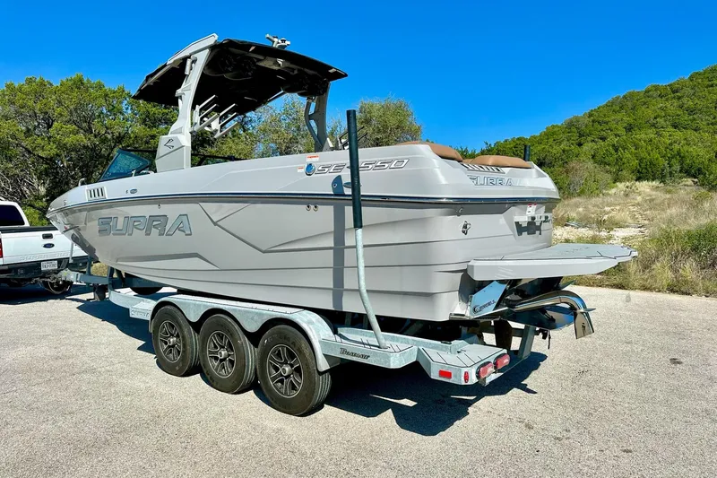 Slide: The Image of 2020 Supra SE550 boat on trailer, parked outdoors under clear blue sky. - 11