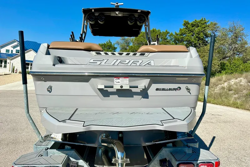 Slide: The Image of 2020 Supra SE550 boat rear view with Swell Surf system, parked outdoors. - 12