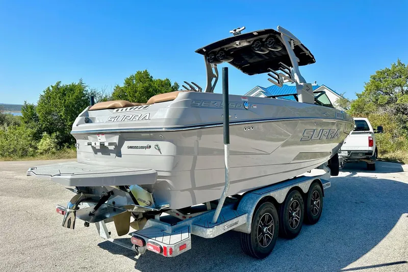 Slide: The Image of 2020 Supra SE550 boat on trailer, parked outdoors under clear blue sky. - 13