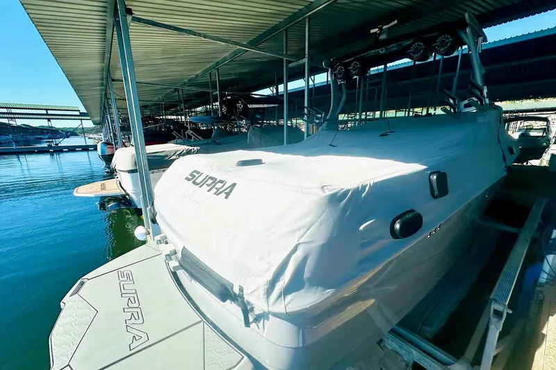 Slide: The Image of 2020 Supra SE550 boat covered and docked in a marina. - 17