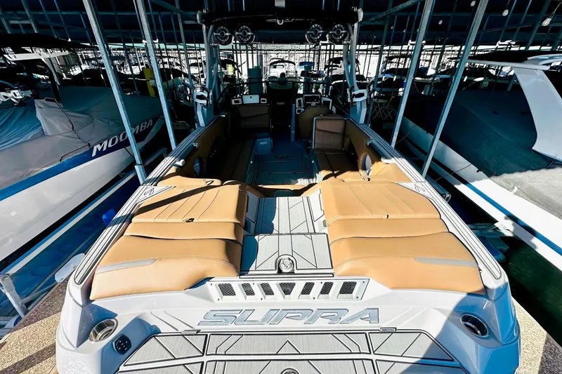 Slide: The Image of 2020 Supra SE550 boat with tan seating, docked in a marina. - 20