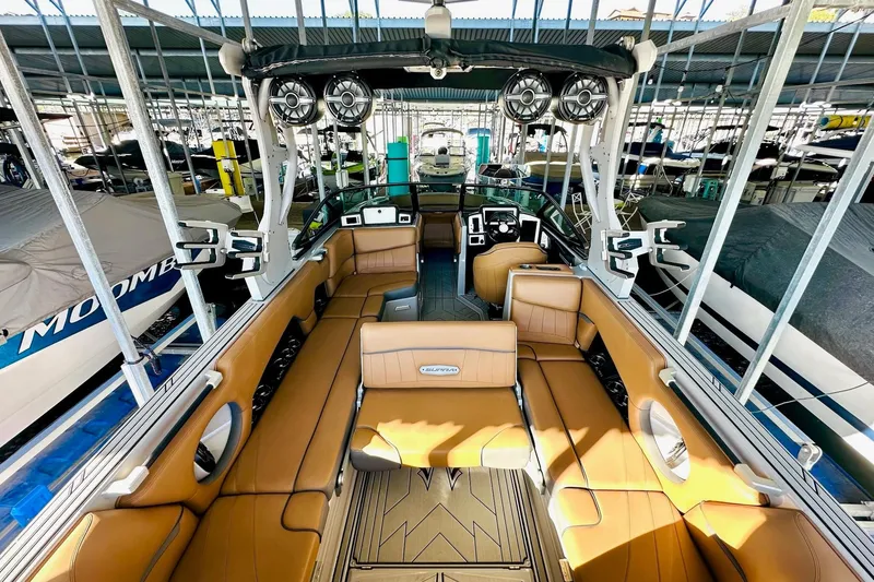 Slide: The Image of 2020 Supra SE550 boat interior with tan seating and advanced audio system in a marina. - 22