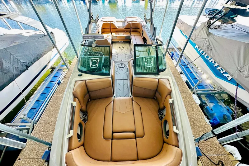 Slide: The Image of 2020 Supra SE550 boat with luxurious tan seating, docked at a marina. - 23