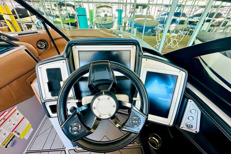 Slide: The Image of 2020 Supra SE550 boat dashboard with steering wheel and digital displays in marina setting. - 32