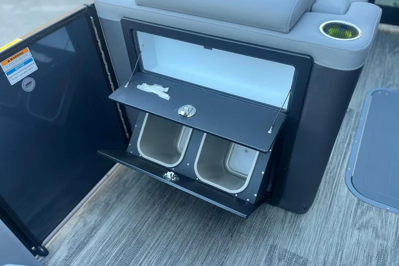 Slide: The Image of Open storage compartment on 2026 Godfrey Monaco 235 SFL boat with dual bins and cup holder. - 15