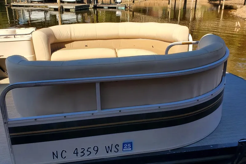 Slide: The Image of 2001 Crestliner LSi 2485 I/O pontoon boat with beige seating, docked by the water. - 3
