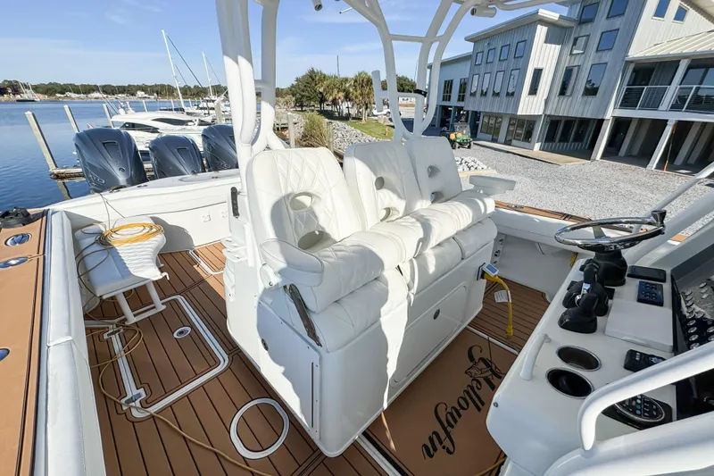 Slide: The Image of 2012 Yellowfin 39 Offshore boat interior with white seating and modern controls at a marina. - 12