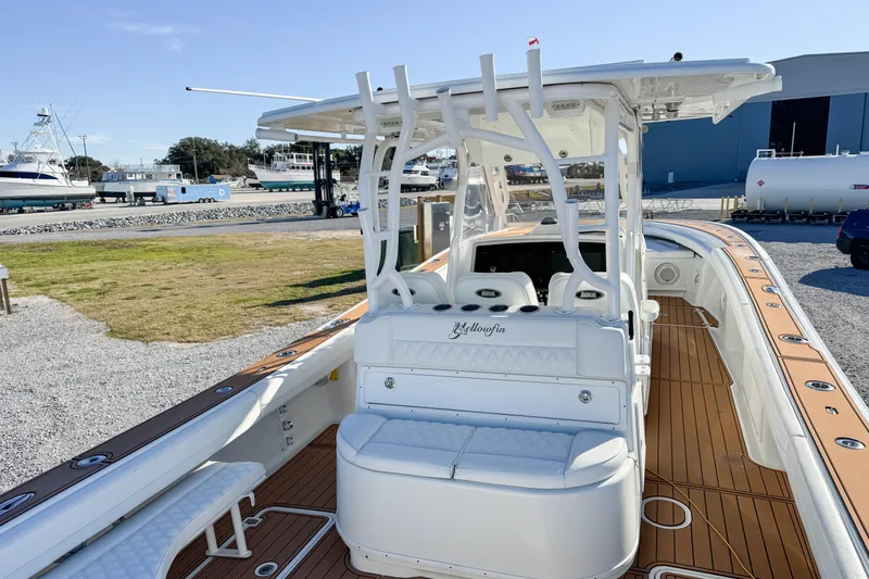 Slide: The Image of 2012 Yellowfin 39 Offshore boat with white seating and wooden deck, docked at a marina. - 13
