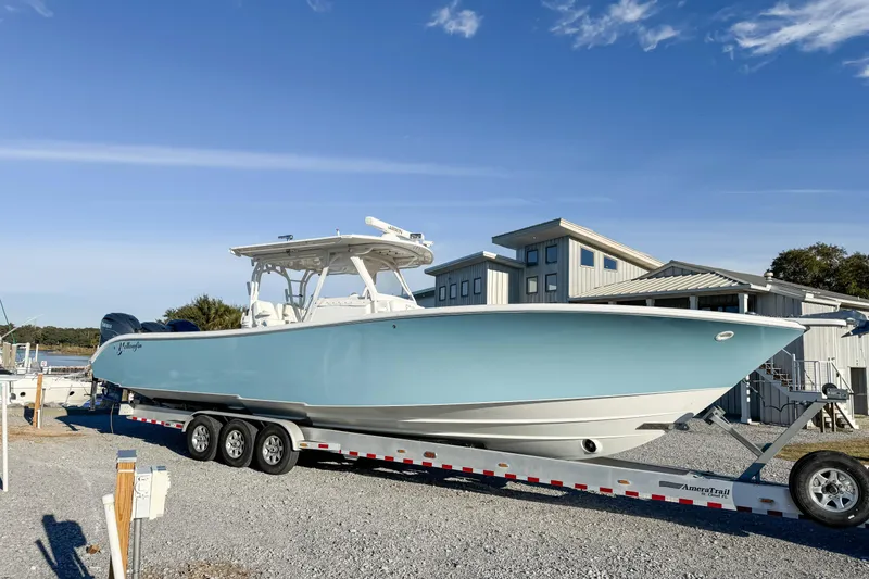 Slide: The Image of 2012 Yellowfin 39 Offshore boat on trailer, parked near modern buildings under clear blue sky. - 14