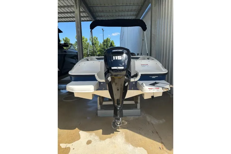 Slide: The Image of 2020 Bayliner Element E18 boat with Mercury 115 outboard motor, parked under a shelter. - 3