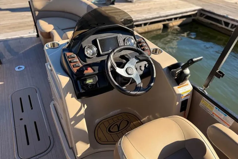 Slide: The Image of 2023 Veranda Relax VR22RC boat dashboard with steering wheel and controls by the water. - 9
