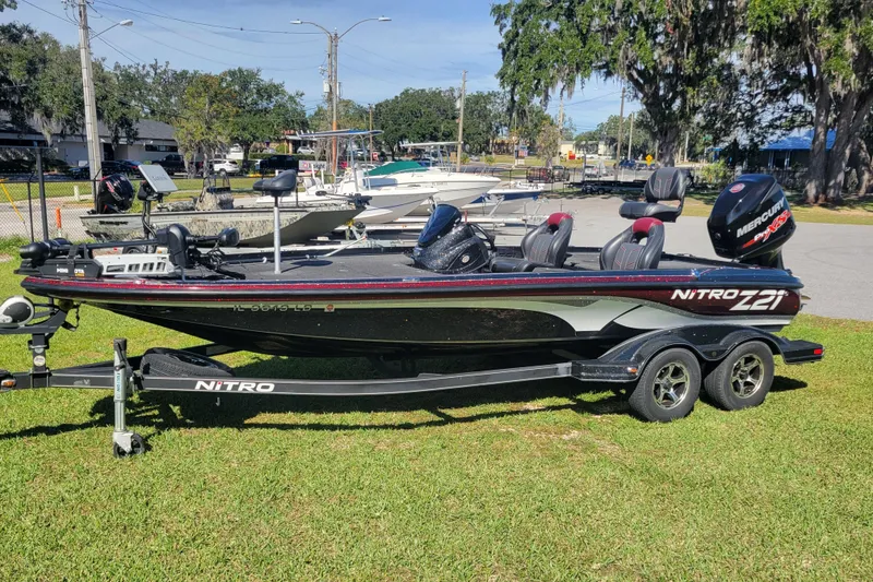 The Image of 2017 Nitro Z21 Pro bass boat on trailer, parked on grass, with Mercury engine. - 1