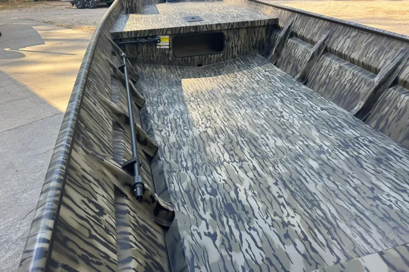 Slide: The Image of 2025 SeaArk 1648 MV Special boat with camouflage interior design, docked on concrete. - 13