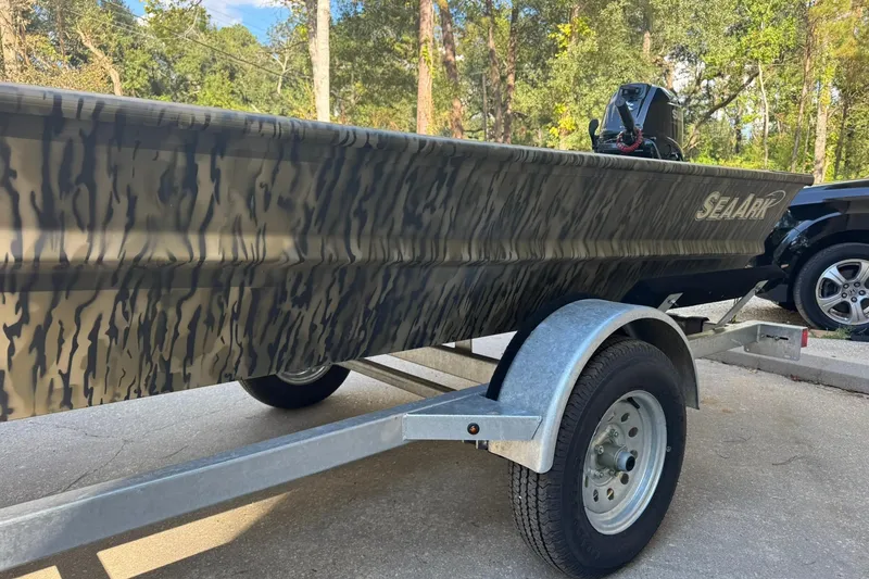 Slide: The Image of 2025 SeaArk 1648 MV Special boat with camouflage design on a trailer. - 15