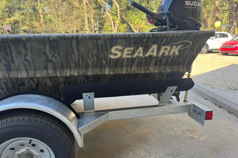 Slide: The Image of 2025 SeaArk 1648 MV Special boat on trailer with Suzuki motor, parked outdoors. - 16