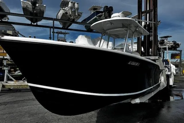 The Image of 2022 NorthCoast 230 Center Console boat on a lift, showcasing sleek black hull design. - 0