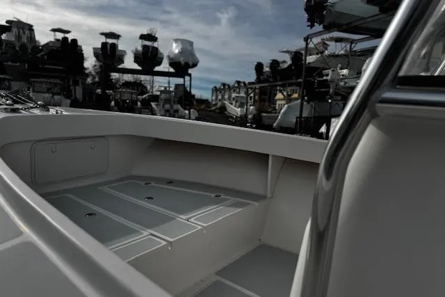 Slide: The Image of 2022 NorthCoast 230 Center Console boat interior with storage compartments, docked under cloudy sky. - 5