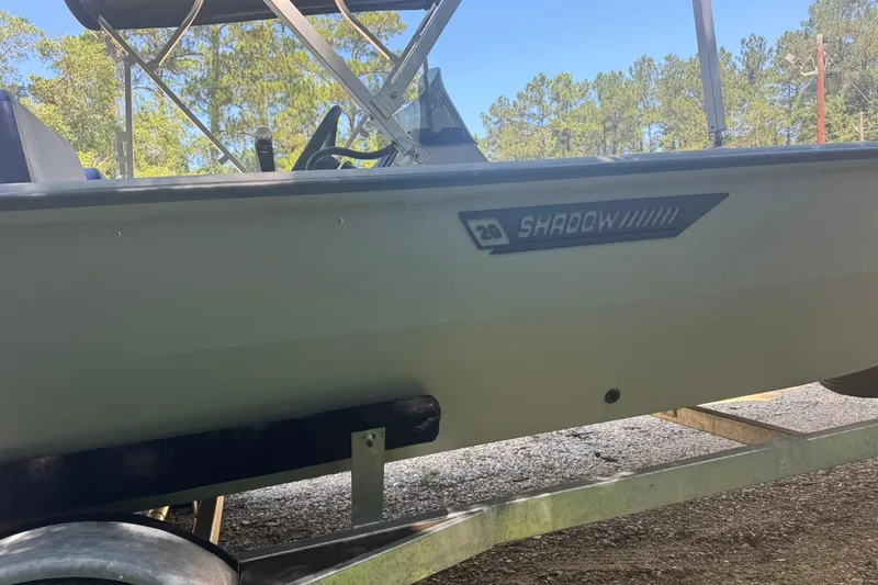 Slide: The Image of 2024 SeaArk Shadow 20 boat on trailer, side view with trees in background. - 10