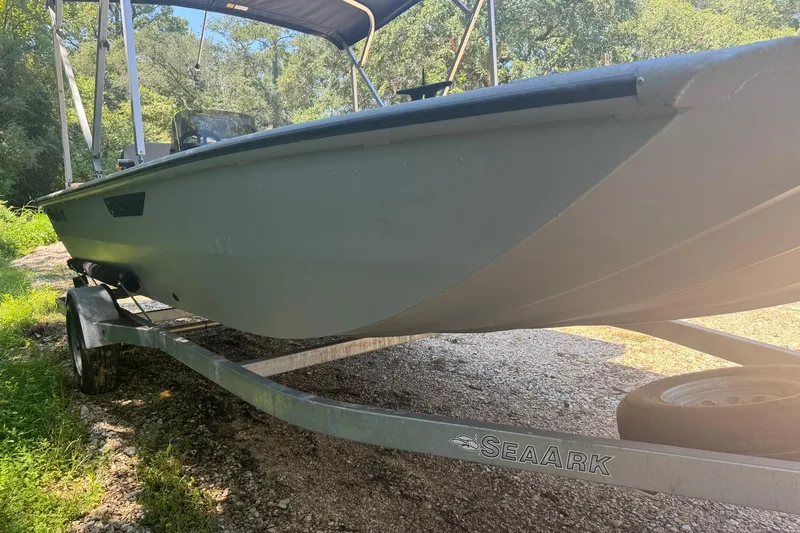 Slide: The Image of 2024 SeaArk Shadow 20 boat on trailer, parked outdoors in a wooded area. - 12