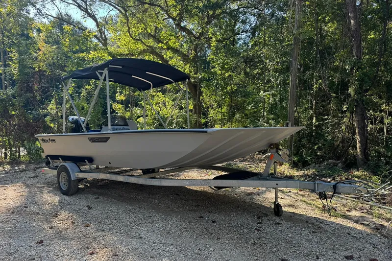Slide: The Image of 2024 SeaArk Shadow 20 boat on trailer, parked in a wooded area. - 22