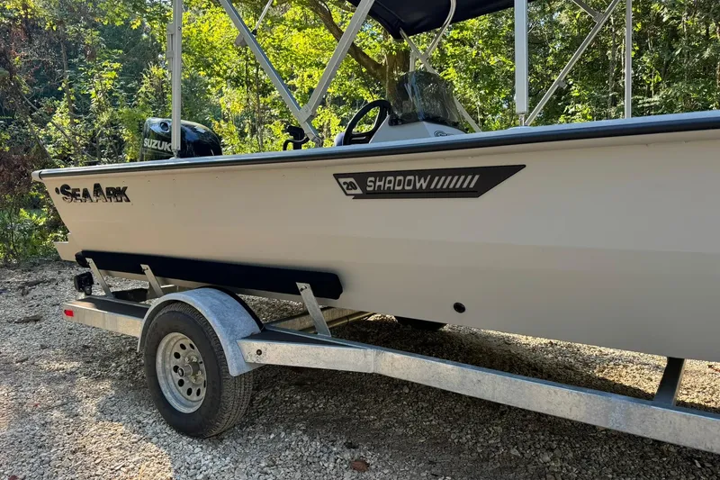 Slide: The Image of 2024 SeaArk Shadow 20 boat on trailer, parked outdoors with Suzuki engine. - 23