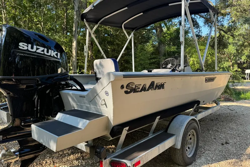 Slide: The Image of 2024 SeaArk Shadow 20 boat with Suzuki engine on trailer, parked outdoors. - 24