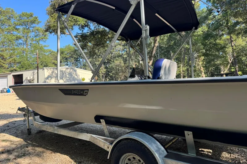 Slide: The Image of 2024 SeaArk Shadow 20 boat on trailer, parked outdoors with trees in background. - 27