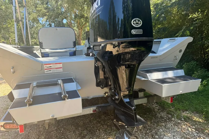 Slide: The Image of 2024 SeaArk Shadow 20 boat with Suzuki outboard motor, rear view in a wooded area. - 5