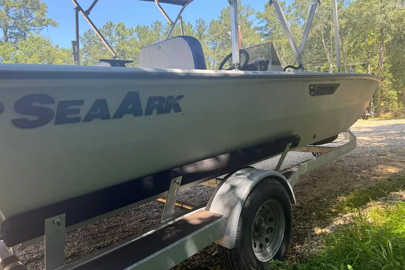 Slide: The Image of 2024 SeaArk Shadow 20 boat on trailer, parked outdoors in a wooded area. - 8