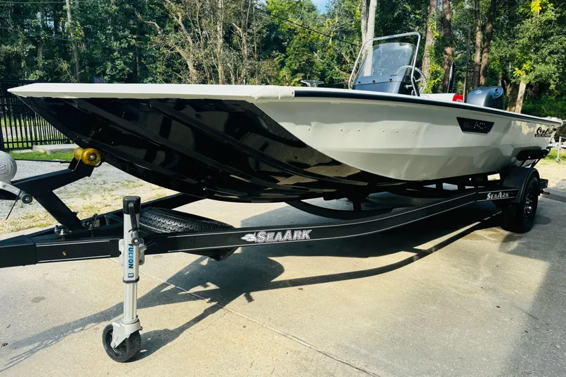 Slide: The Image of 2024 SeaArk Shadow 19 v boat on trailer, parked outdoors, showcasing sleek design. - 17